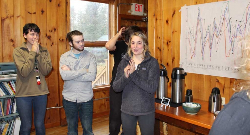 A person speaks to a group of people in front of a chart during the family seminar of an outward bound intercept course.